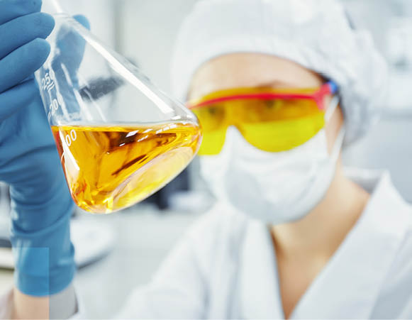 Close up portrait of young woman s hands holding test tube with yellow liquid  Medical researcher or doctor wearing surgical mask and safety glasses looking at glass tube while working in laboratory 
